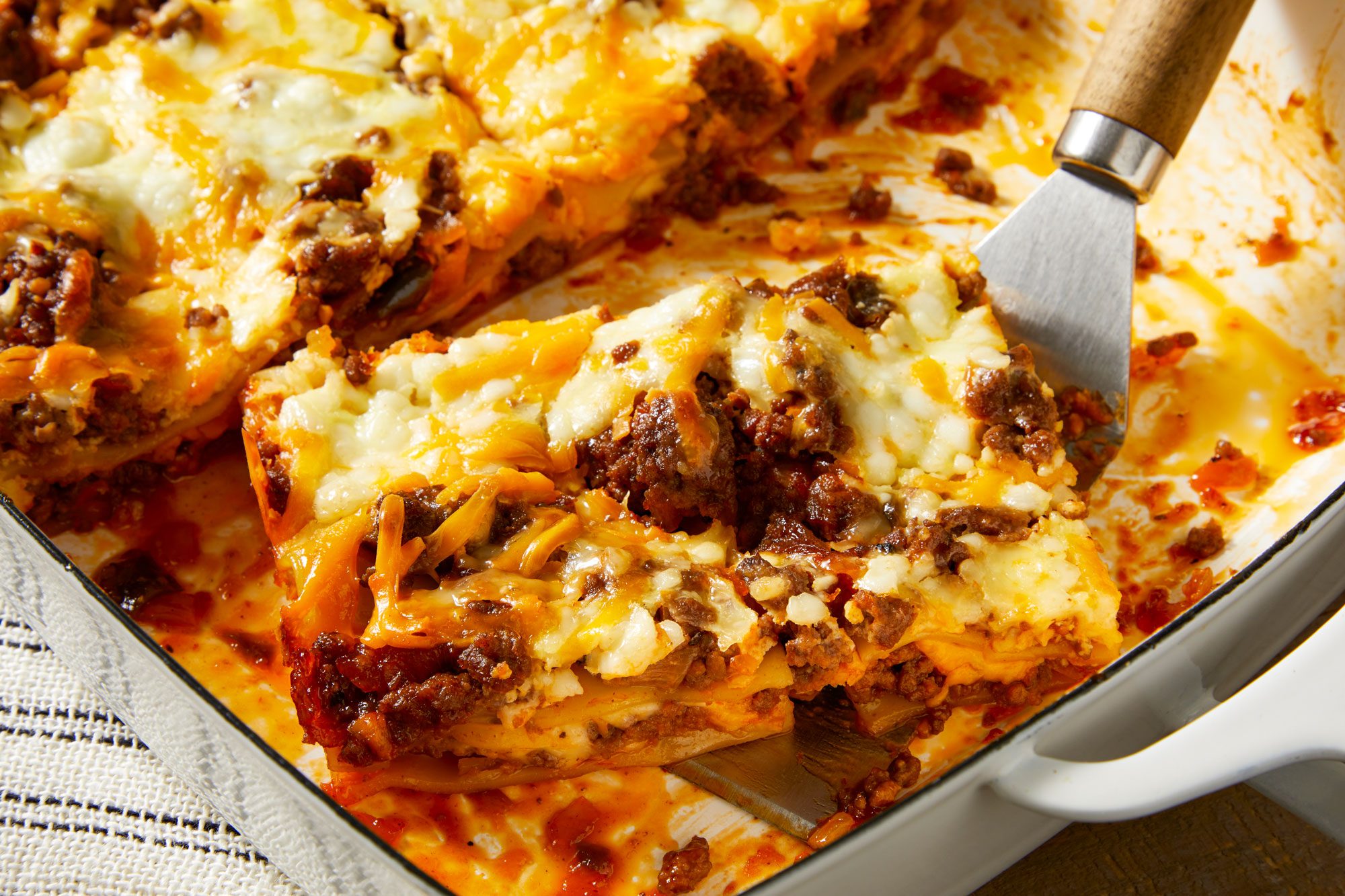 closeup shot of a rectangular baking dish filled with Barbecue Lasagna, with one piece partially removed and resting on a spatula