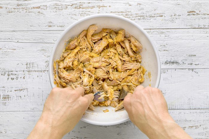 chicken being shredded with two forks