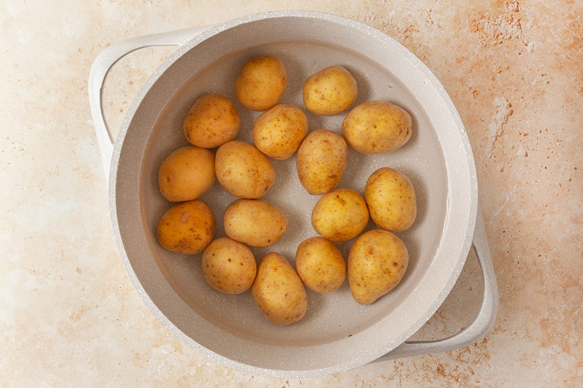 Baby potatoes placed soaked in water in large pot