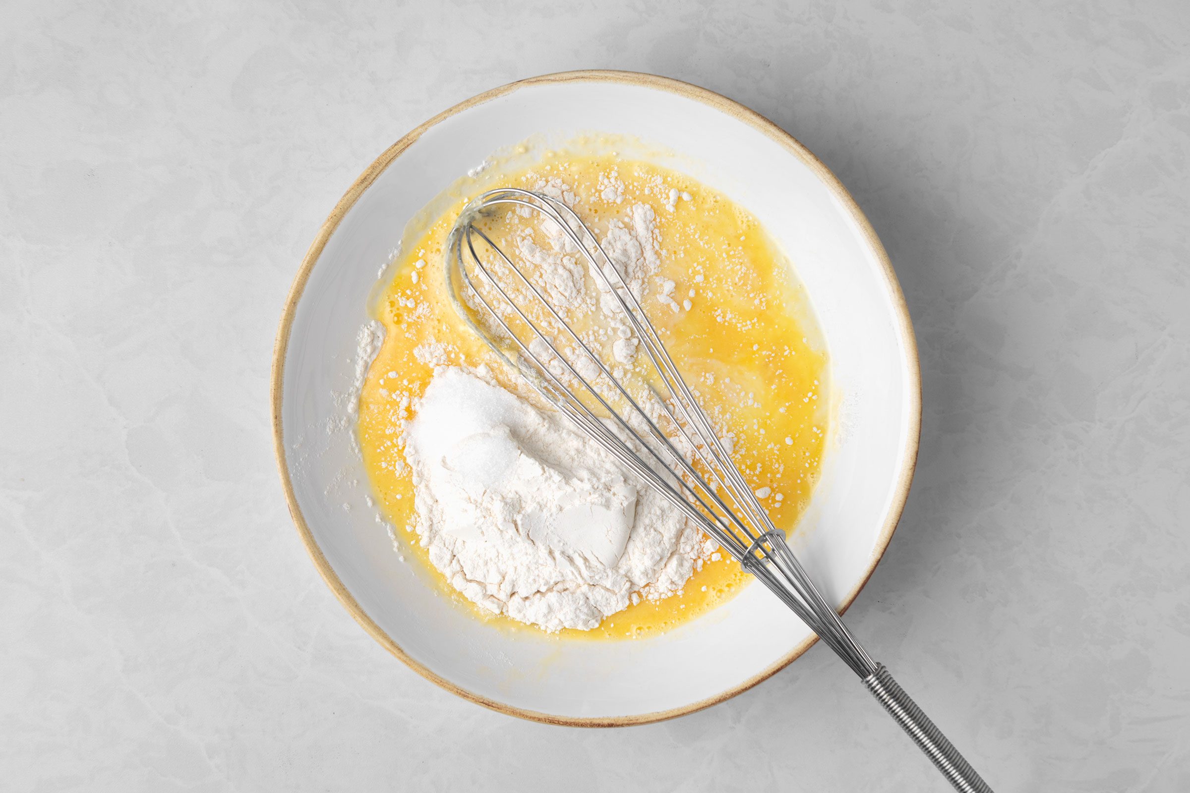 In a bowl, using a whisk to beat the eggs until they’re very light in color.