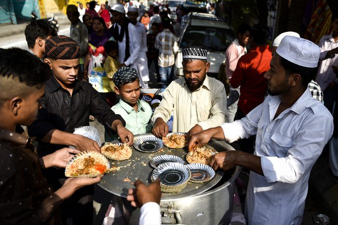 People gather to be served biryani rice from a street vendor during Eid-al-Adha