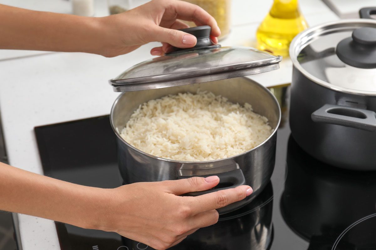 Woman cooking rice on stove in kitchen