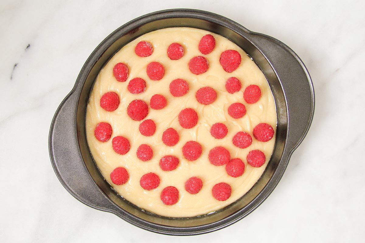 Batter is evenly spreaded into the pan topped with raspberries