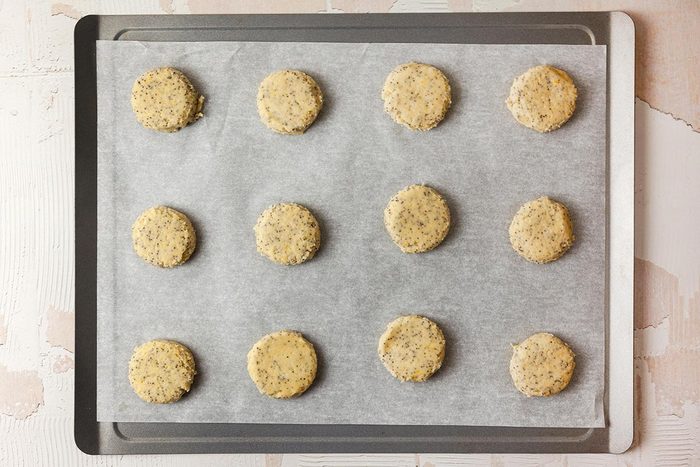 Baking tray lined with parchment paper, on which there are neatly arranged circular dough pieces