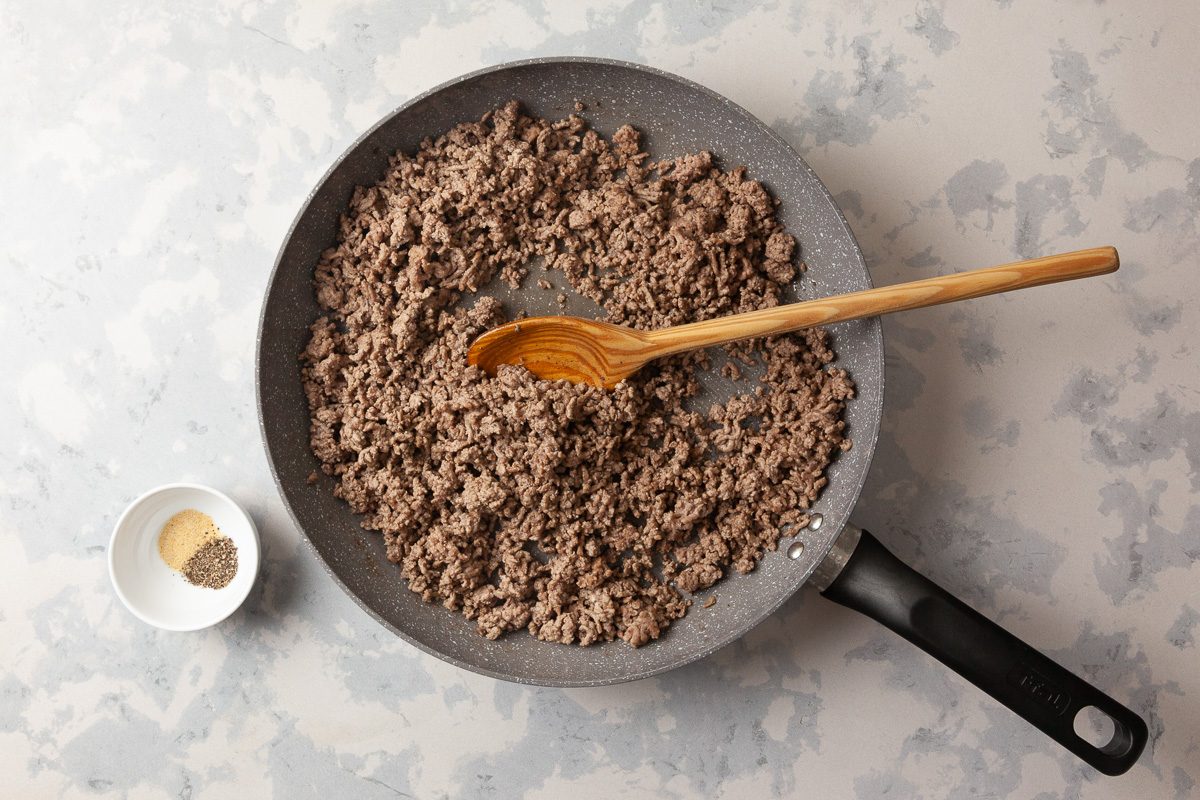cooked ground beef in a skillet next to pepper
