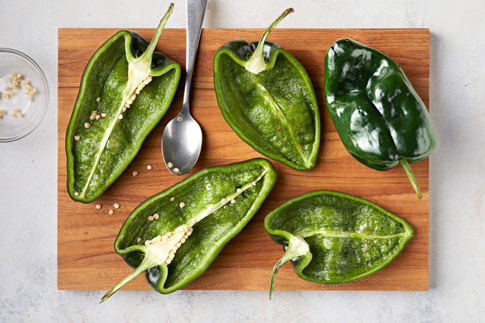 poblano peppers cut in half on a chopping board