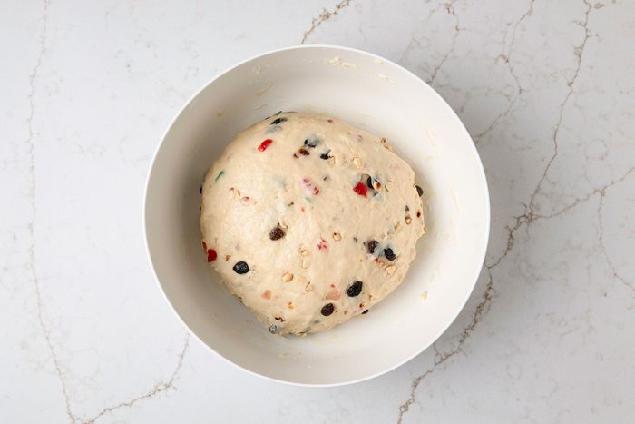 overhead shot of a bowl filled with a light colored dough the bowl is placed on a light marbled surface underneath
