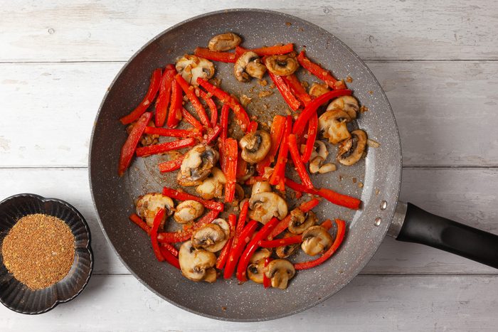 mushrooms, bell peppers being sautéed in a skillet