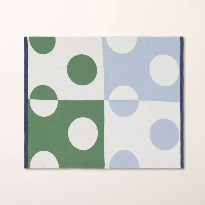 Green and light blue Kate Spade Throw Blanket on a tan background