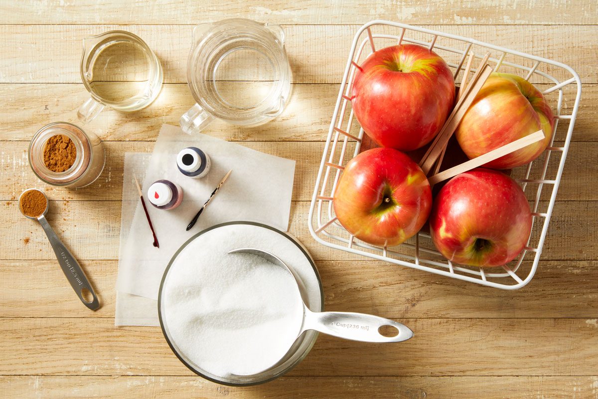 Overhead shot of all ingredients for Candy Apples; all set on a light brown wooden surface;