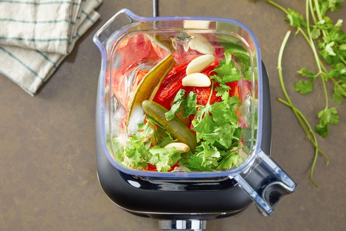 Overhead shot of place broth; vegetables; garlic; cilantro and salt in a high-speed blender; puree until smooth; Set aside; a napkin; all set on a light brown surface