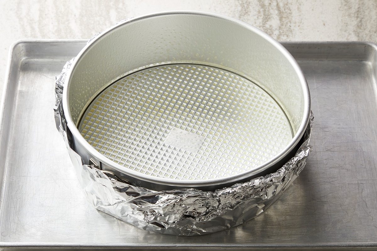 Place a greased 9 inch springform pan on a double thickness of heavy duty foil about 18 inch square; Wrap foil securely around pan; Place on a baking sheet