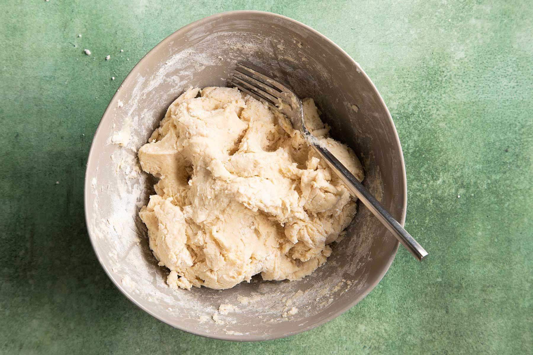 Overhead shot of flour mixture kept in white bowl kept on top of a green marble countertop.