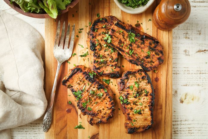 Grilled Boneless Pork Chops on a wooden board with a fork.
