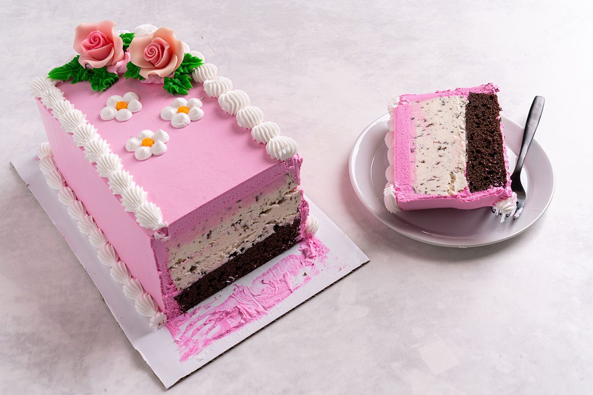 Pink ice cream cake with a slice next to it on a plate with a fork