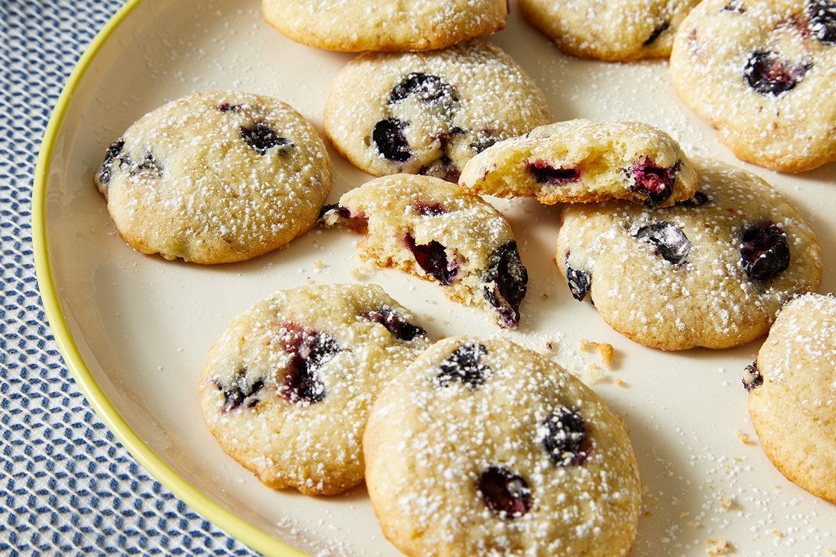 A close-up of a plate filled with cookies, generously sprinkled with powdered sugar on top.