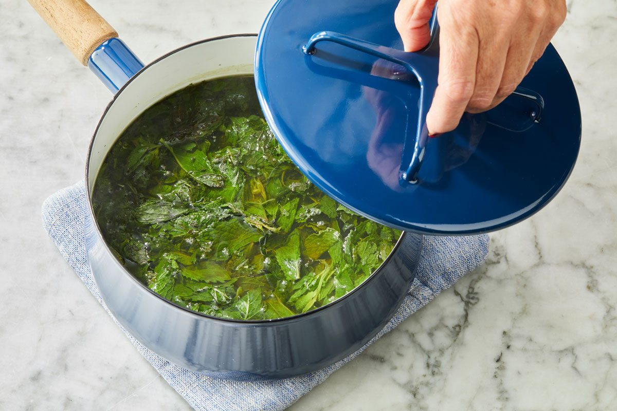Overhead shot of a large saucepan; bring water and mint to a boil; Remove from heat; cover and let stand 15 minutes; napkin; marble surface;