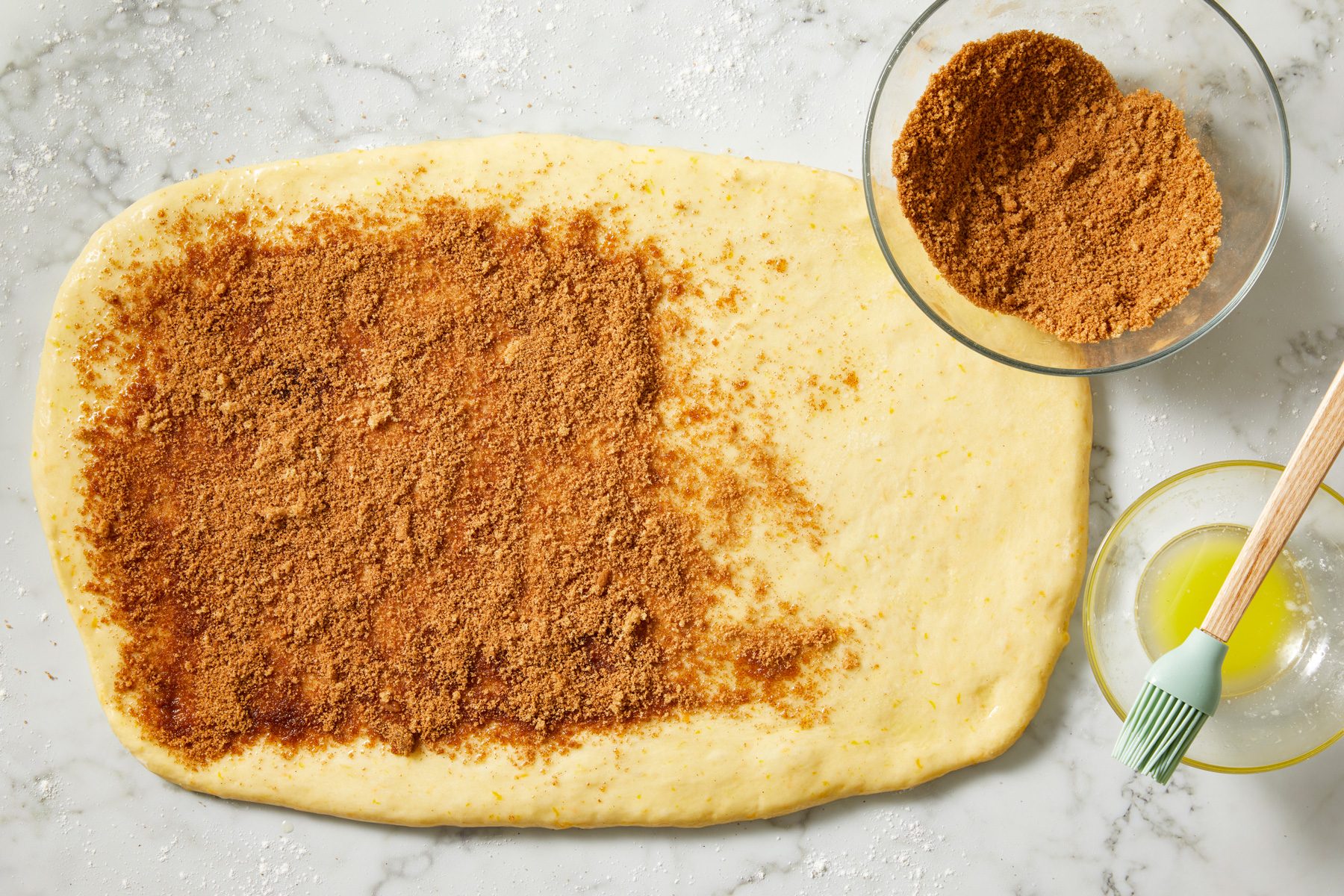 Overhead shot; On a lightly floured surface; roll out dough into an 18x12-inch rectangle; Mix brown sugar and cinnamon; Brush with butter; sprinkle with the brown sugar mixture to within 1/2 inch of edges; marble surface;