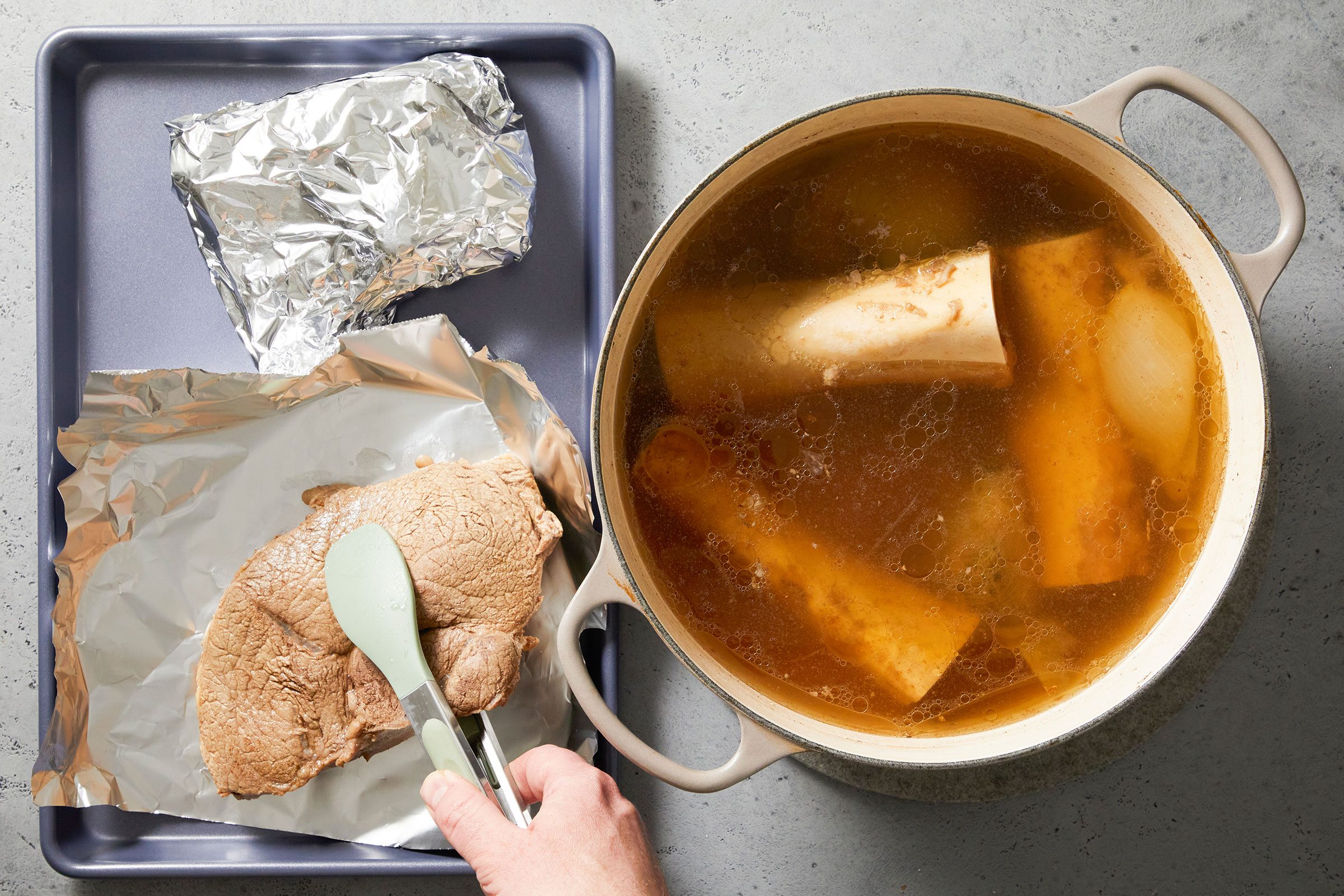Transferring the beef from the stockpot to a foil sheet on baking dish