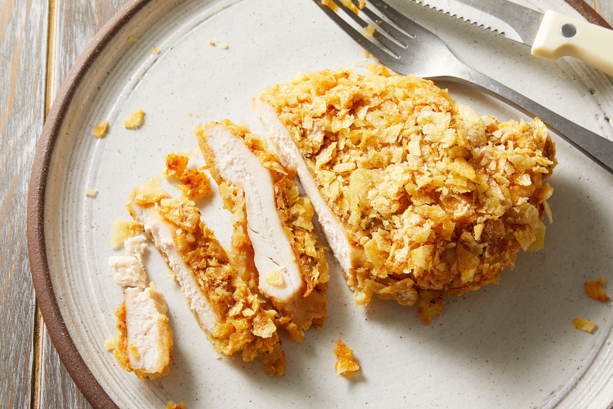 Potato Chip Chicken sliced into a few pieces on a white plate with a fork.