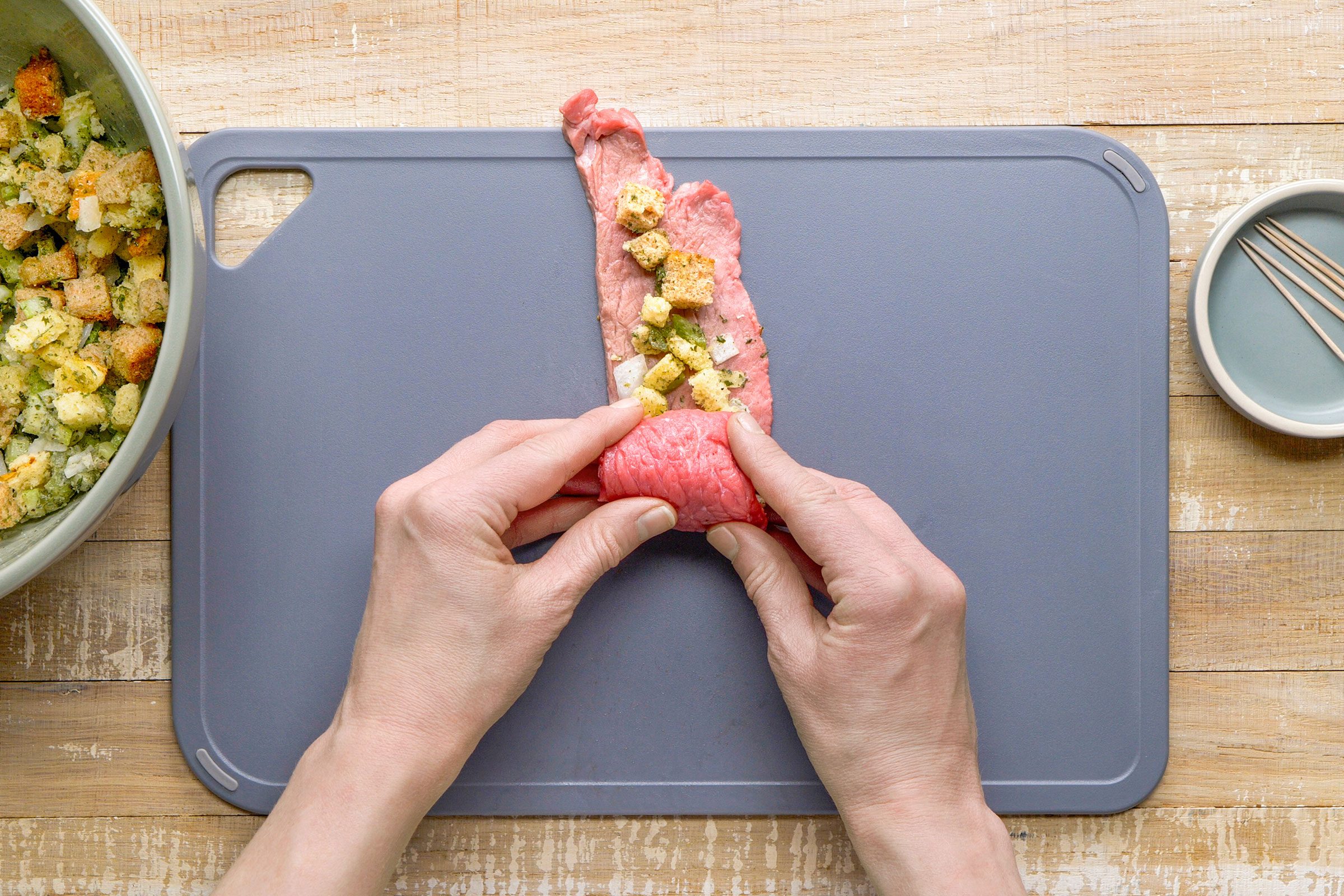 Rolling up and fastening the filled meat piece with a toothpick.