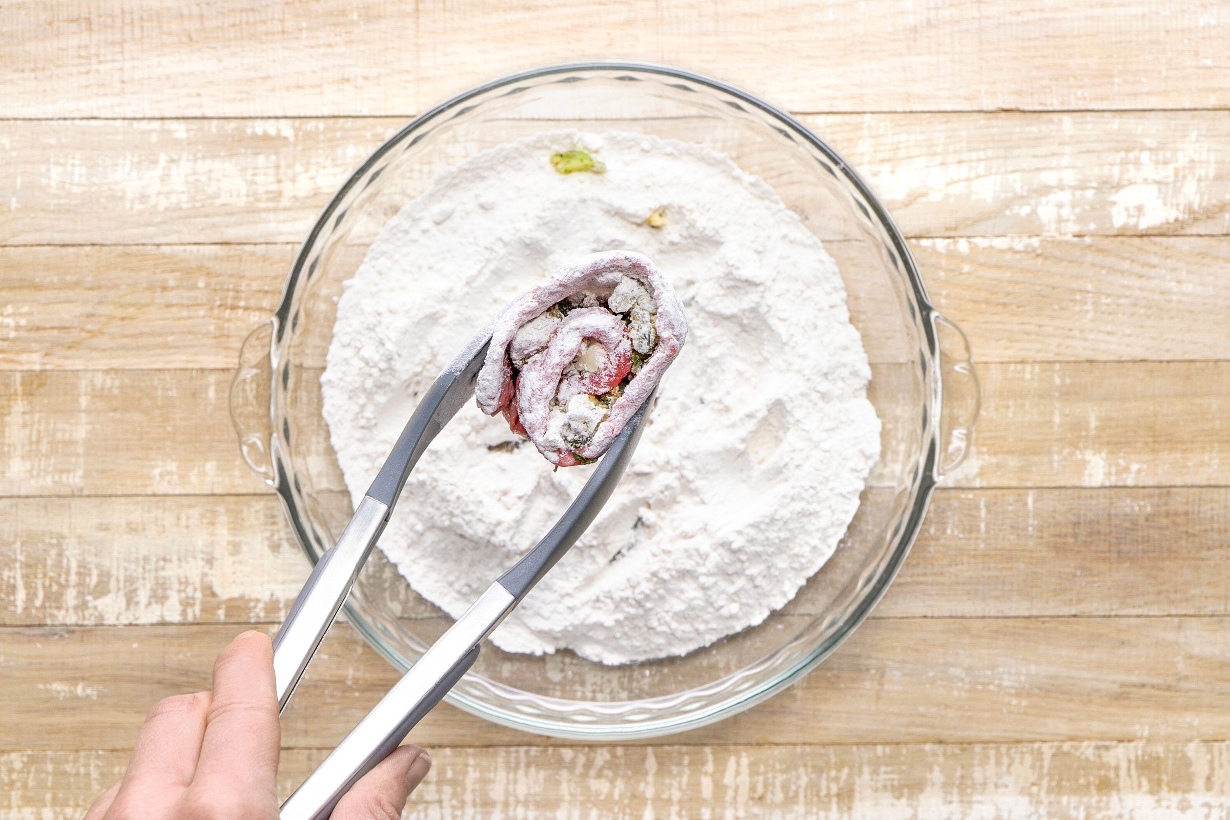 Rolling a meat roll with filling in flour.