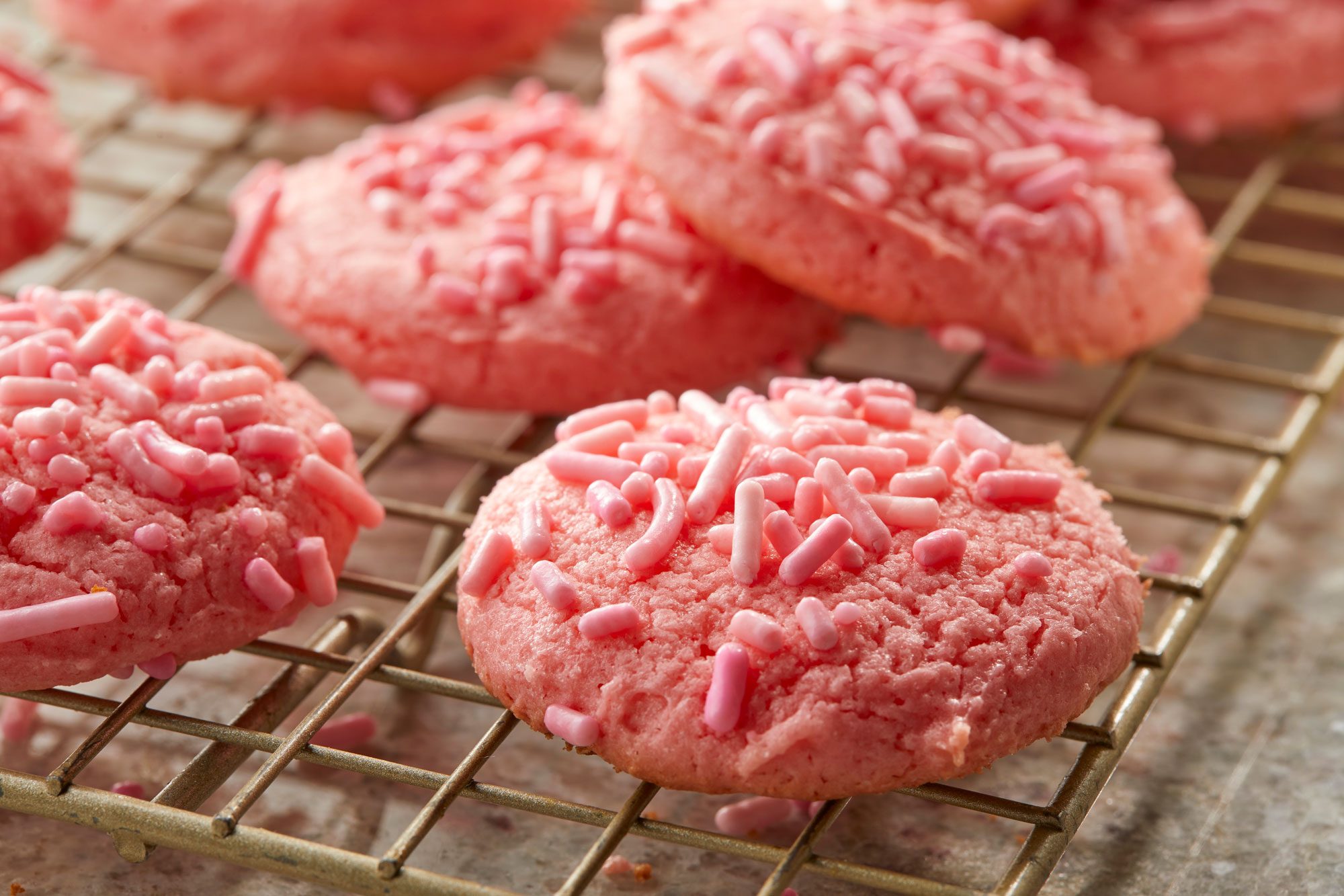 Close-up shot of Strawberry Cake Mix Cookies; served over wire rack on a marble surface