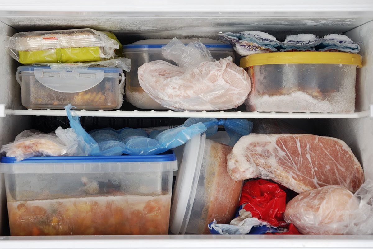Frozen food inside a freezer. Lots of leftovers in plastic containers.