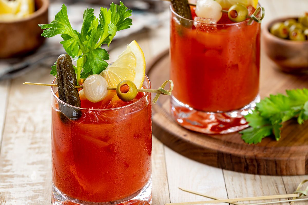 Bloody mary cocktail with garnishes on wooden table