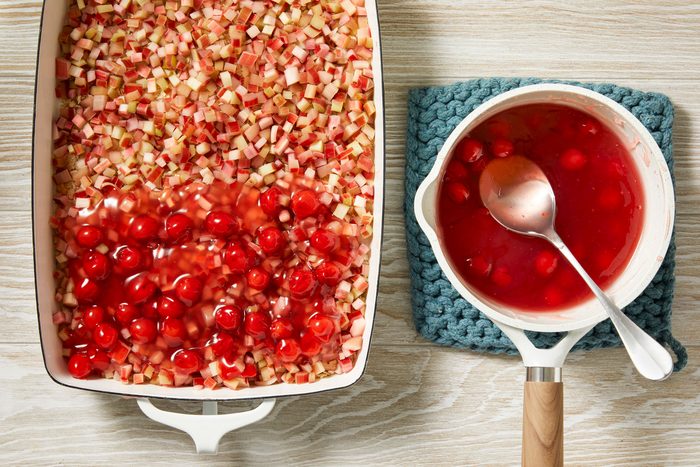 Overhead shot; remove saucepan; stir in extract and cherry pie filling; spoon over rhubarb; cream wooden surface