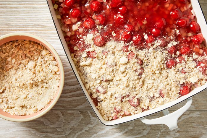 Overhead shot of combine nuts with reserved crumb mixture; sprinkle over cherries; Bake until filling is bubbly and topping is lightly browned 40-45 minutes; cream wooden surface