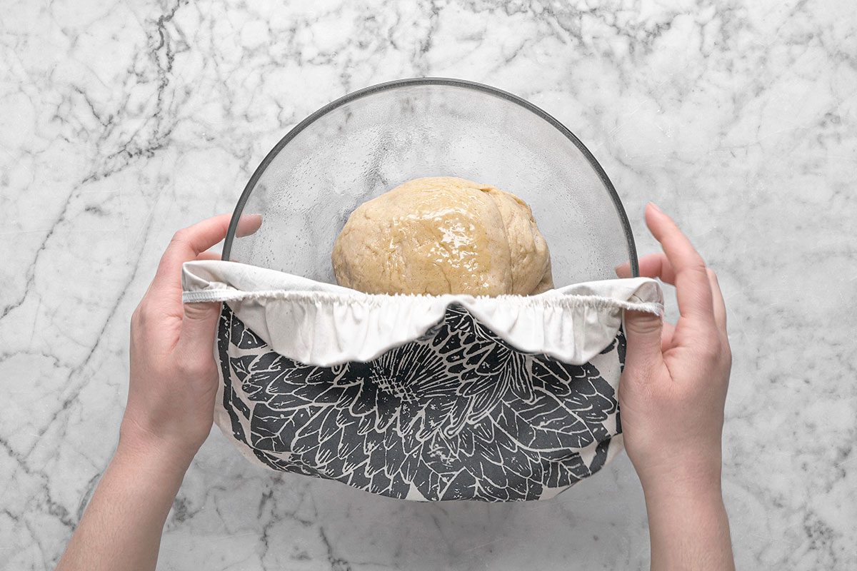 Dough is being covered in a bowl