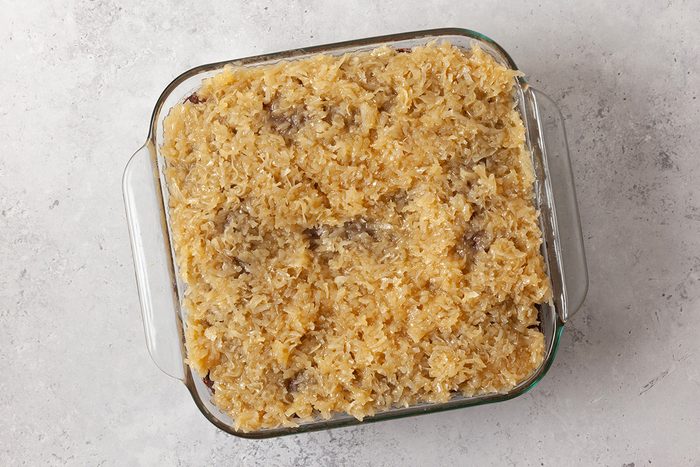 A glass baking dish filled with a baked casserole featuring a golden, crumbly topping, set on a light-colored surface.