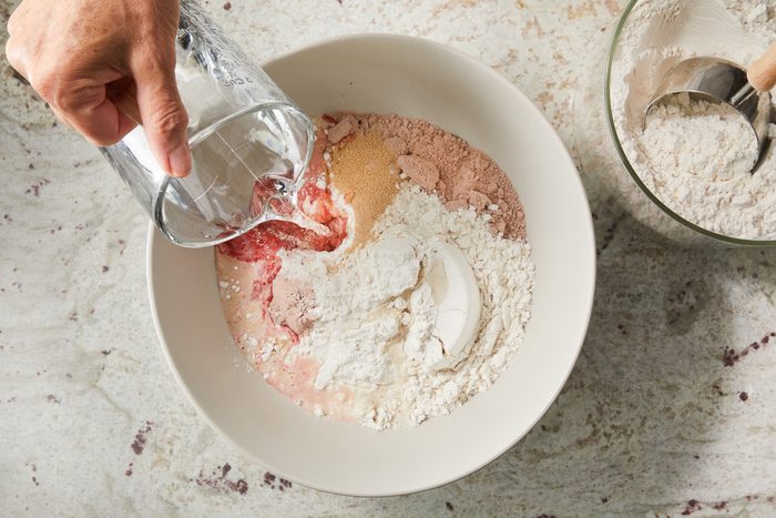 adding water to dough mixture in a large bowl