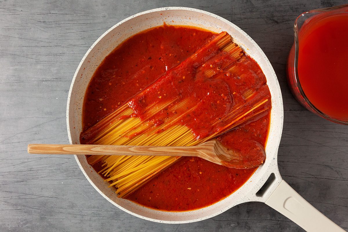Add remaining 2 cups passata sauce and Add spaghetti pushing it down into the tomato sauce; spoon sauce over the top