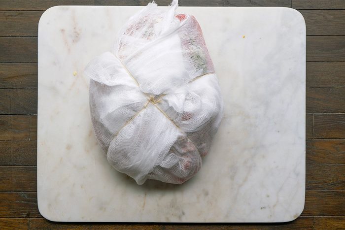 Overhead shot of cheesecloth on a white cutting board on a table. Place the stuffed ham on a double thickness of cheesecloth; bring up corners of cloth and tie tightly with kitchen string.