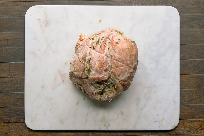 Overhead shot of stuffed ham on a white cutting board kept on a table.