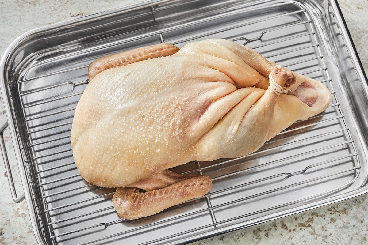 A raw chicken on a metal tray.