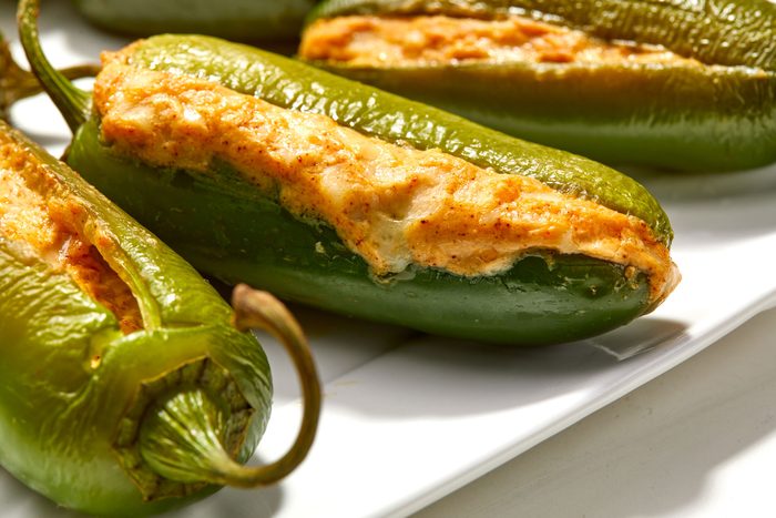 Closeup shot of Grilled Stuffed Jalapenos serve warm on a large white platter; all set on a white surface