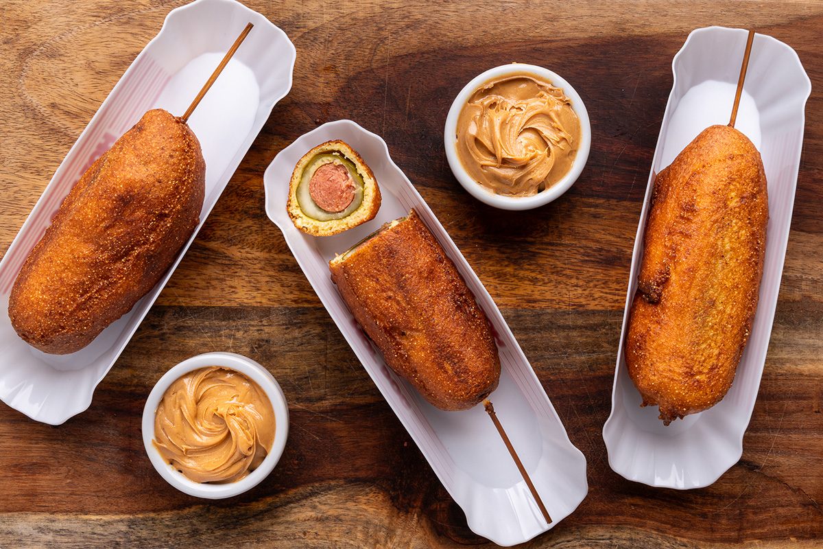 Fried pickle hot dogs with peanut dips on a table