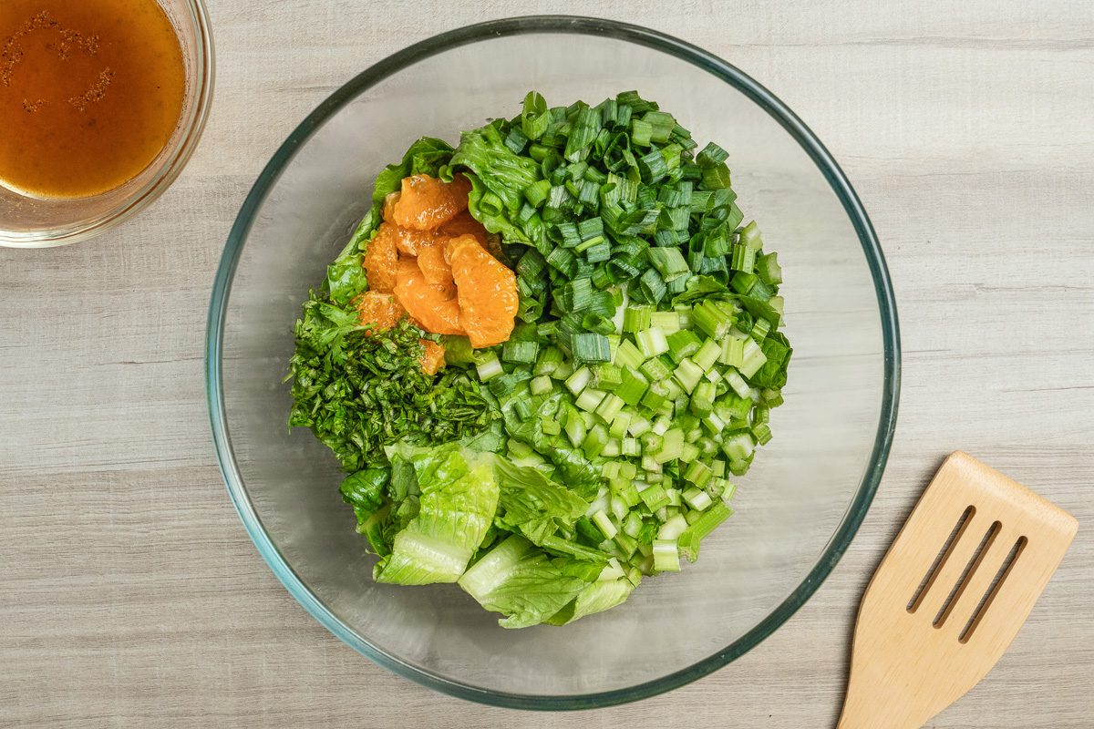 romaine, mandarin oranges, celery, green onions and fresh parsley in a bowl