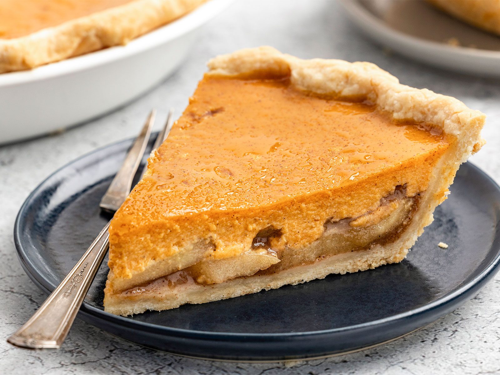 slice of pumpkin apple pie with a fork on a black plate