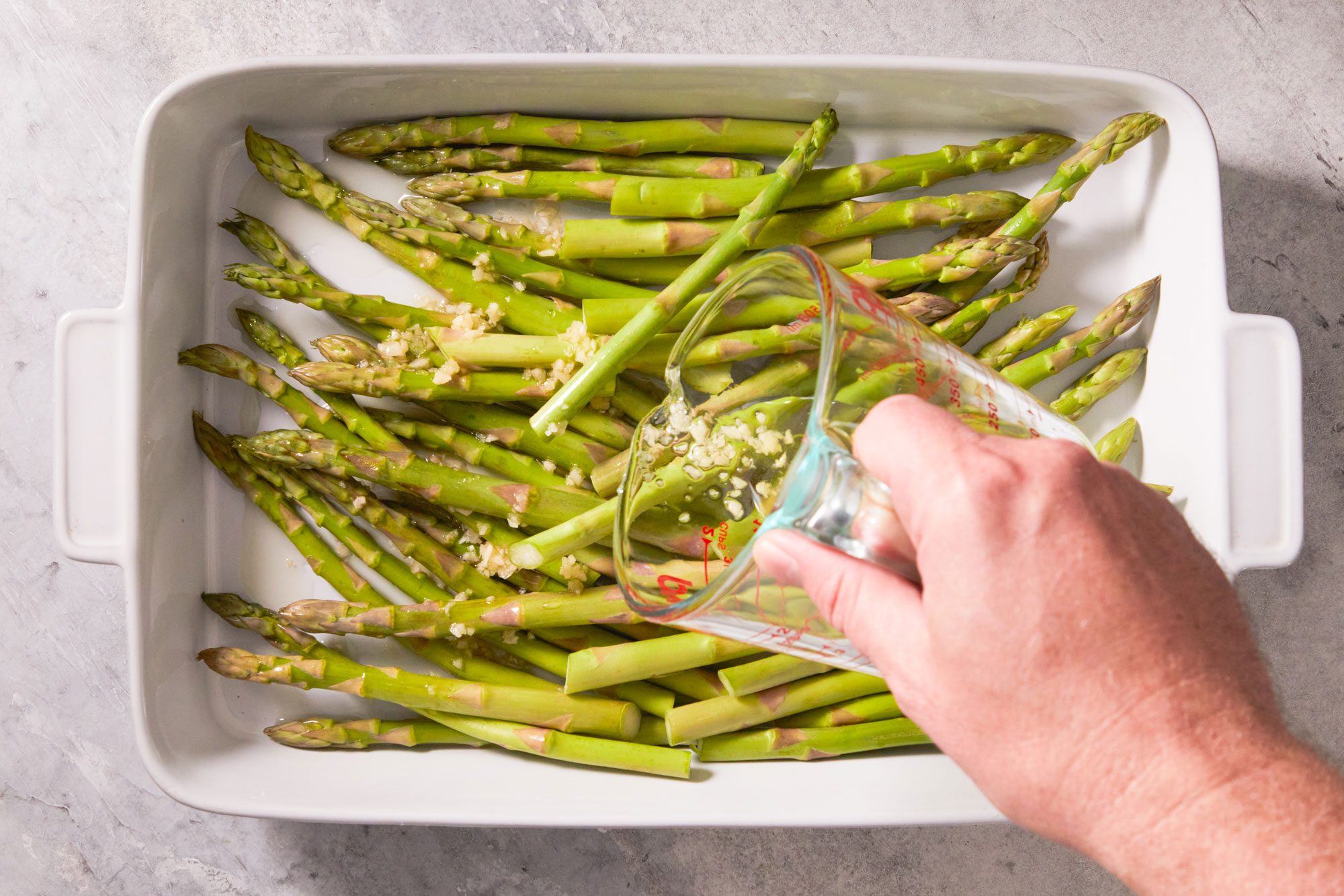 Place asparagus in a baking dish , pour oilve oil and garlic mix over asparagus and turn to coat.