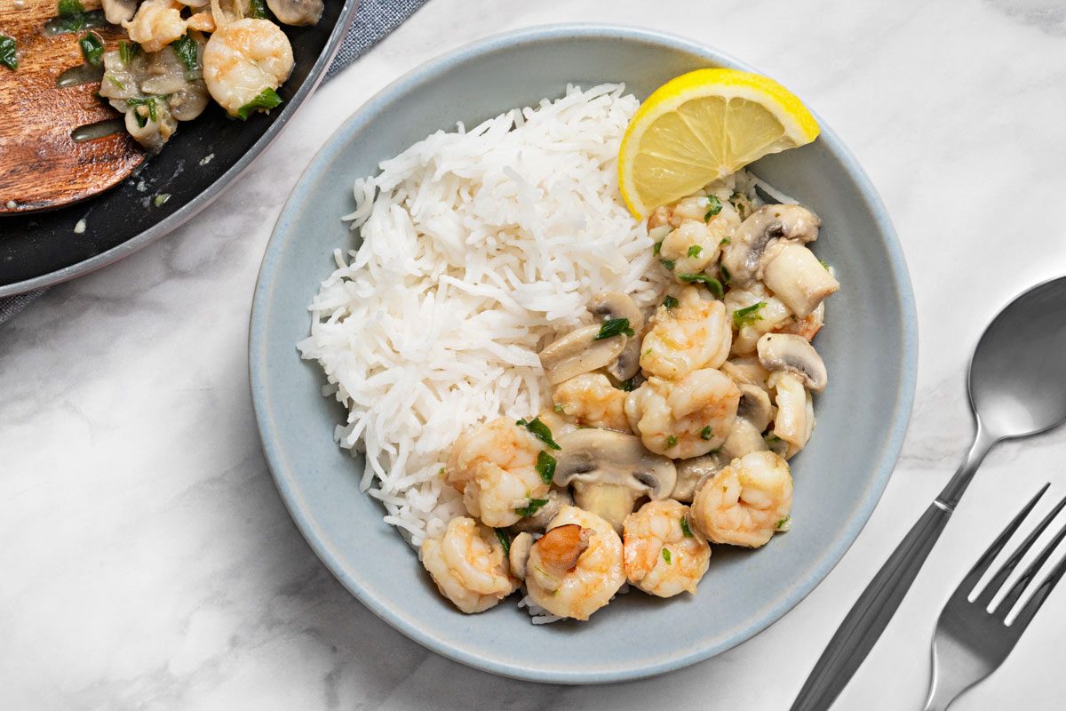 Overhead shot of Stir-Fried Shrimp and Mushrooms served with rice and lemon slice