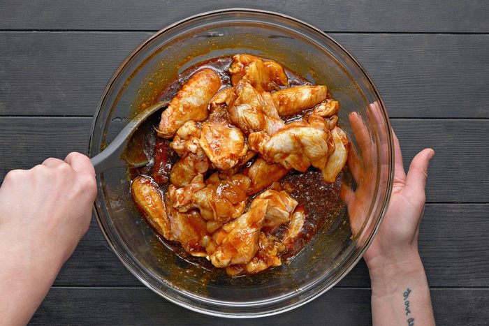 chicken being marinated by being tossed in a bowl