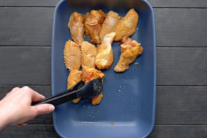 chicken being arranged on a greased 13x9-inch baking dish
