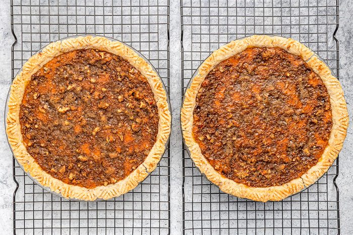 Two pecan pies with golden-brown crusts and nutty, textured tops are cooling on wire racks placed on a light gray surface.