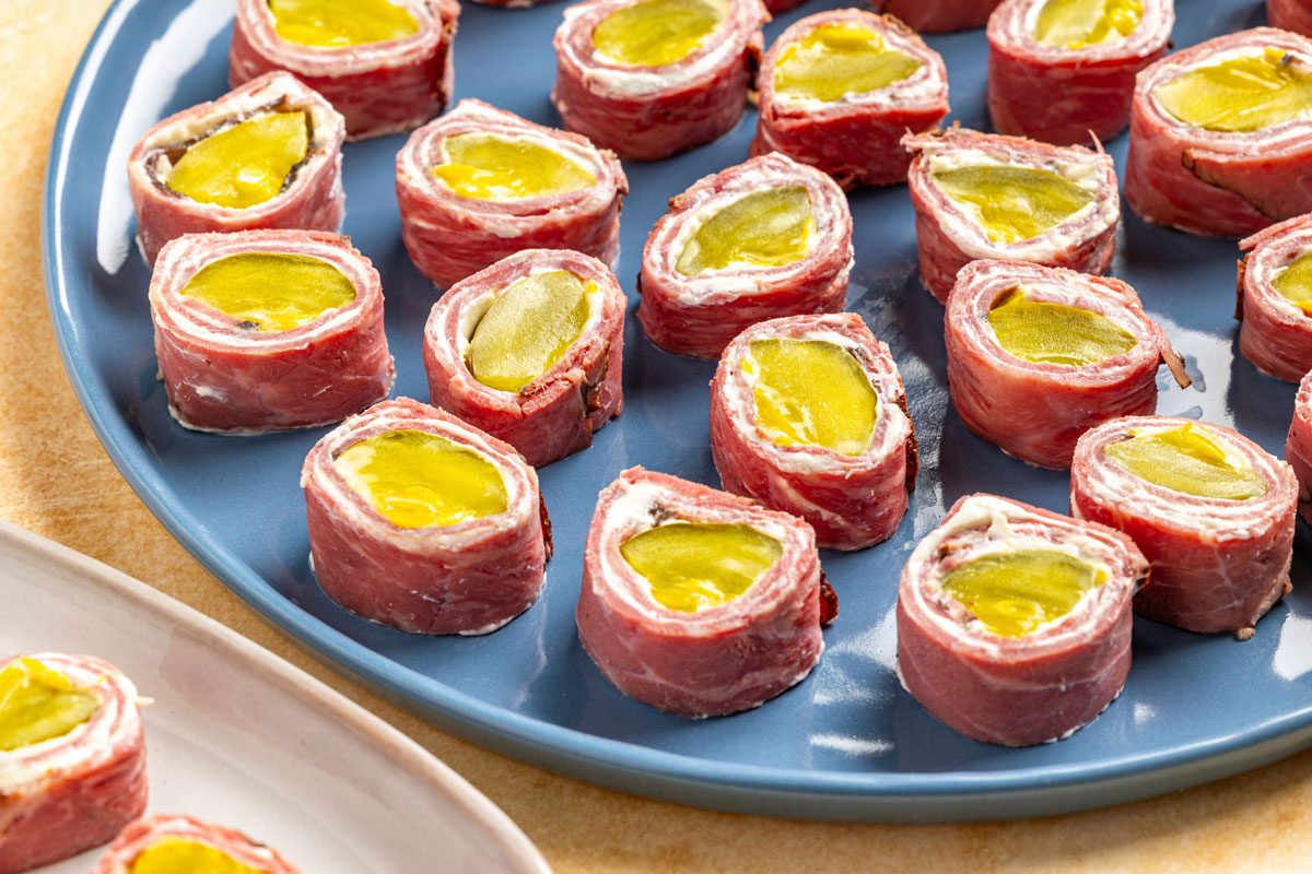 3/4th hsot of A blue plate filled with neatly arranged Pastrami Roll Ups