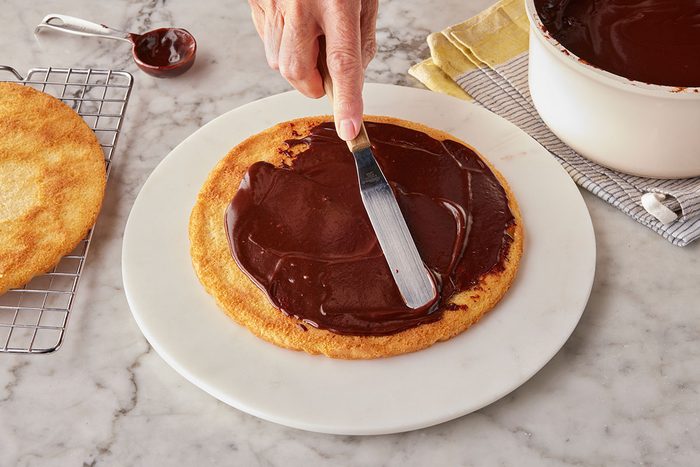 Frosting being layered on the top of the baked base for cake