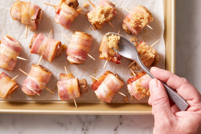 Placing the bacon-wrapped sausage bites on a parchment or foil-lined 15x10x1-inch baking pan.